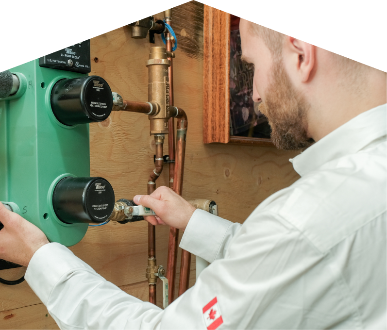 Mr. Furnace HVAC specialist performing boiler installation, securing a valve on a new hydronic heating system with copper piping and a green circulation pump mounted on a wooden wall.