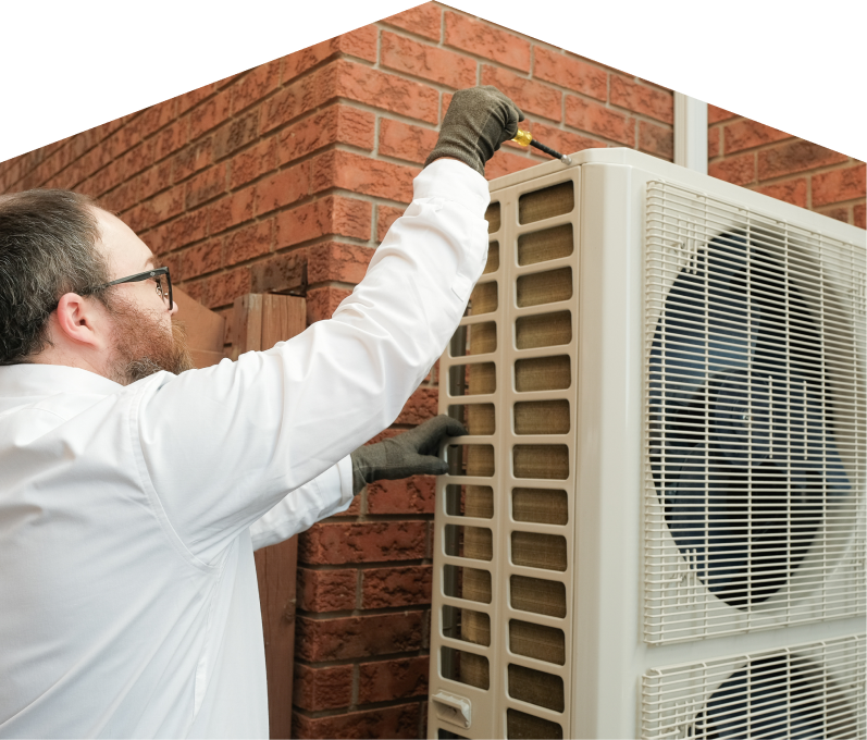Mr. Furnace HVAC specialist using a screwdriver to complete a heat pump installation beside a brick wall. Mr. Furnace HVAC specialist using a screwdriver to complete a heat pump installation beside a brick wall.