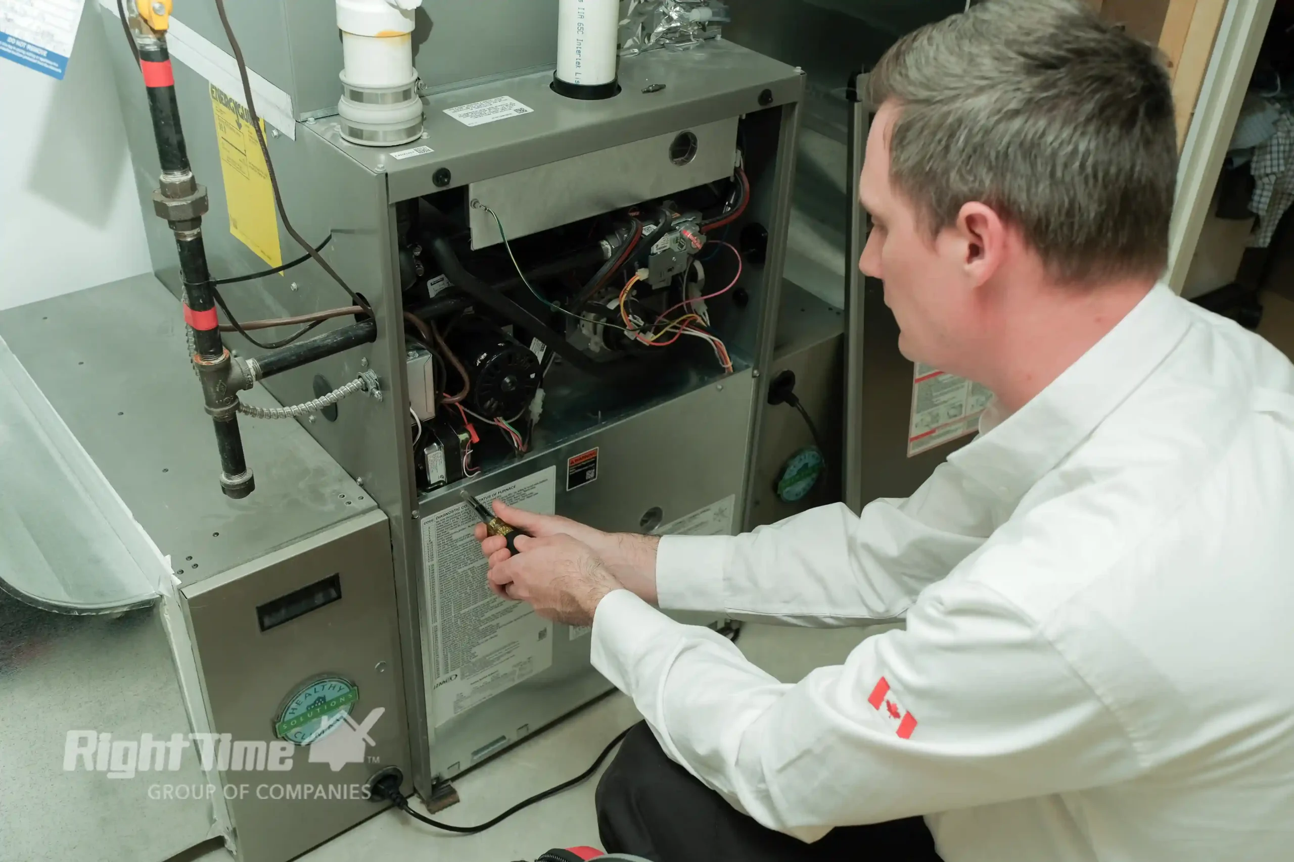 HVAC technician adjusting components inside an open residential gas furnace during maintenance.